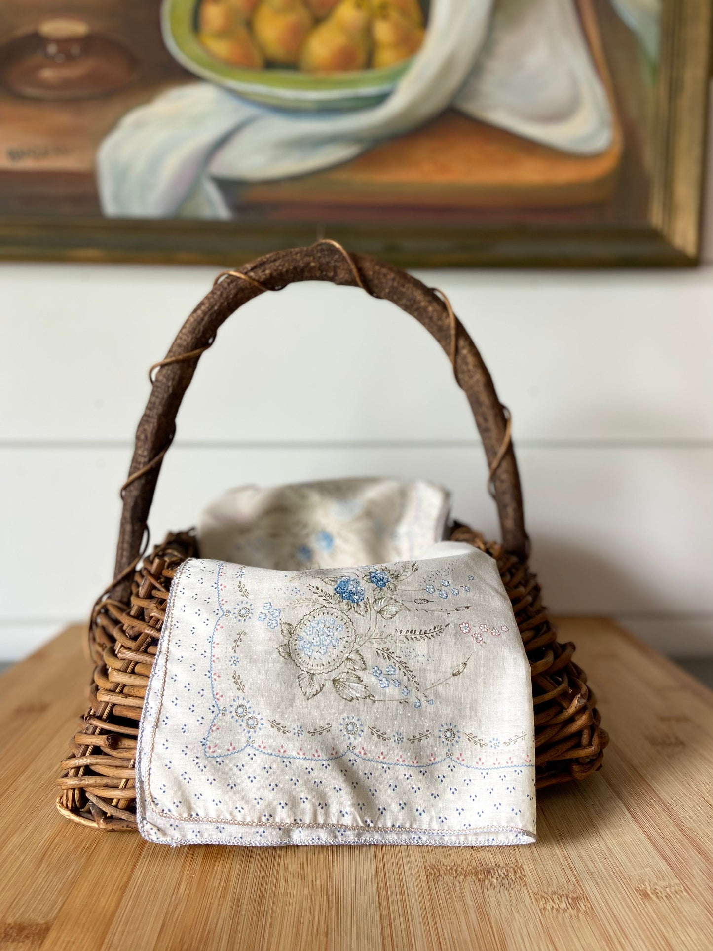 "A set of four vintage cream napkins with touches of blue and pink, ideal for table settings."