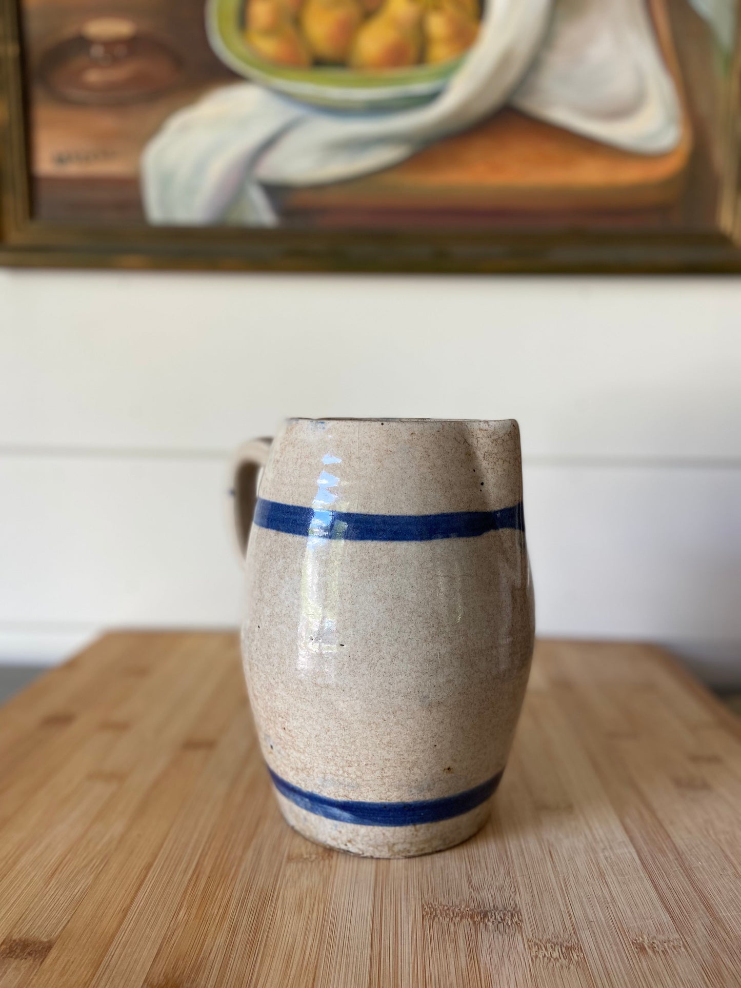 "A solid stoneware pitcher with blue stripes, ideal for displaying flowers or serving beverages."