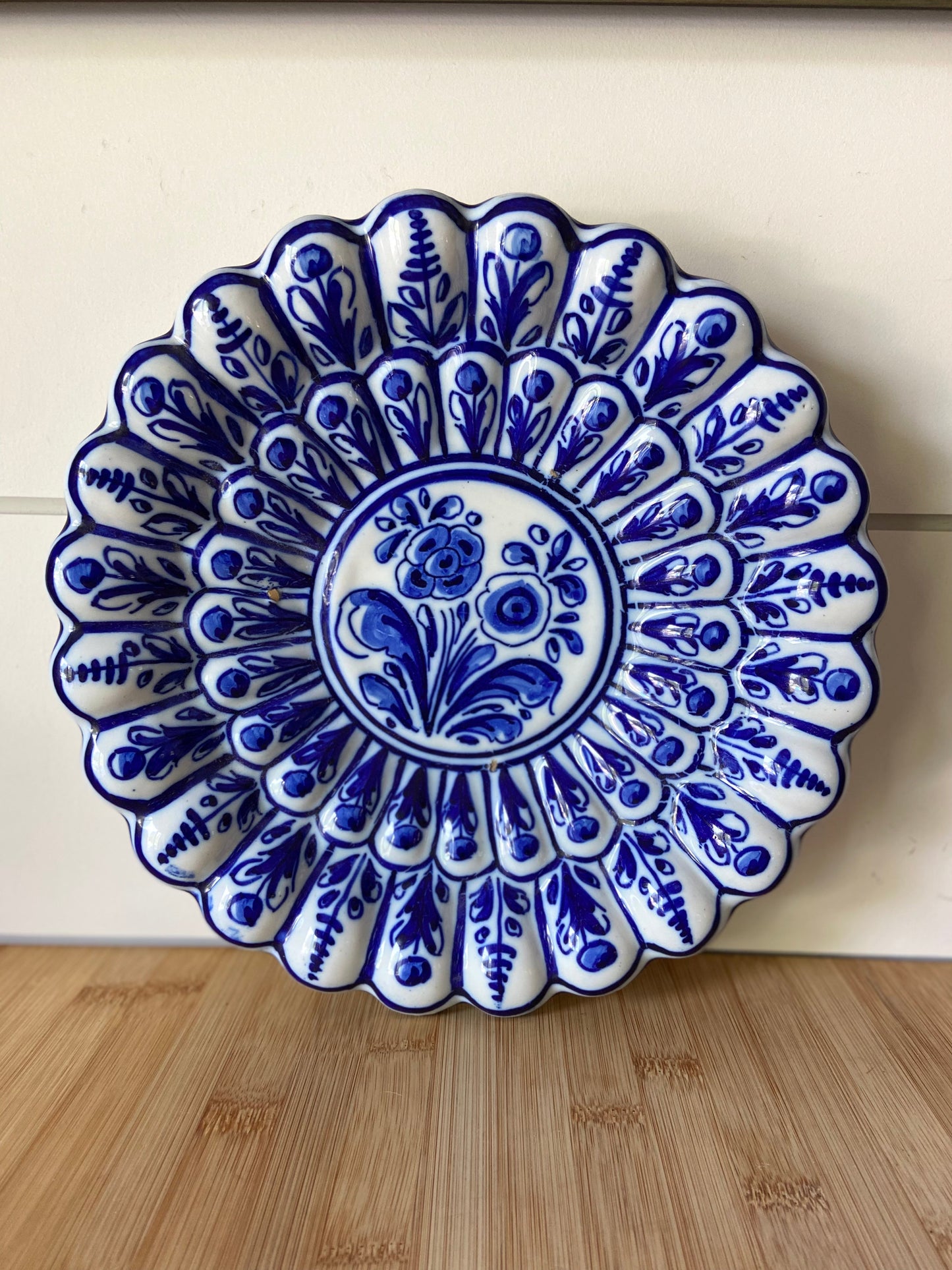 "A blue and white bowl with scalloped detailing, ready to hang for a decorative touch."