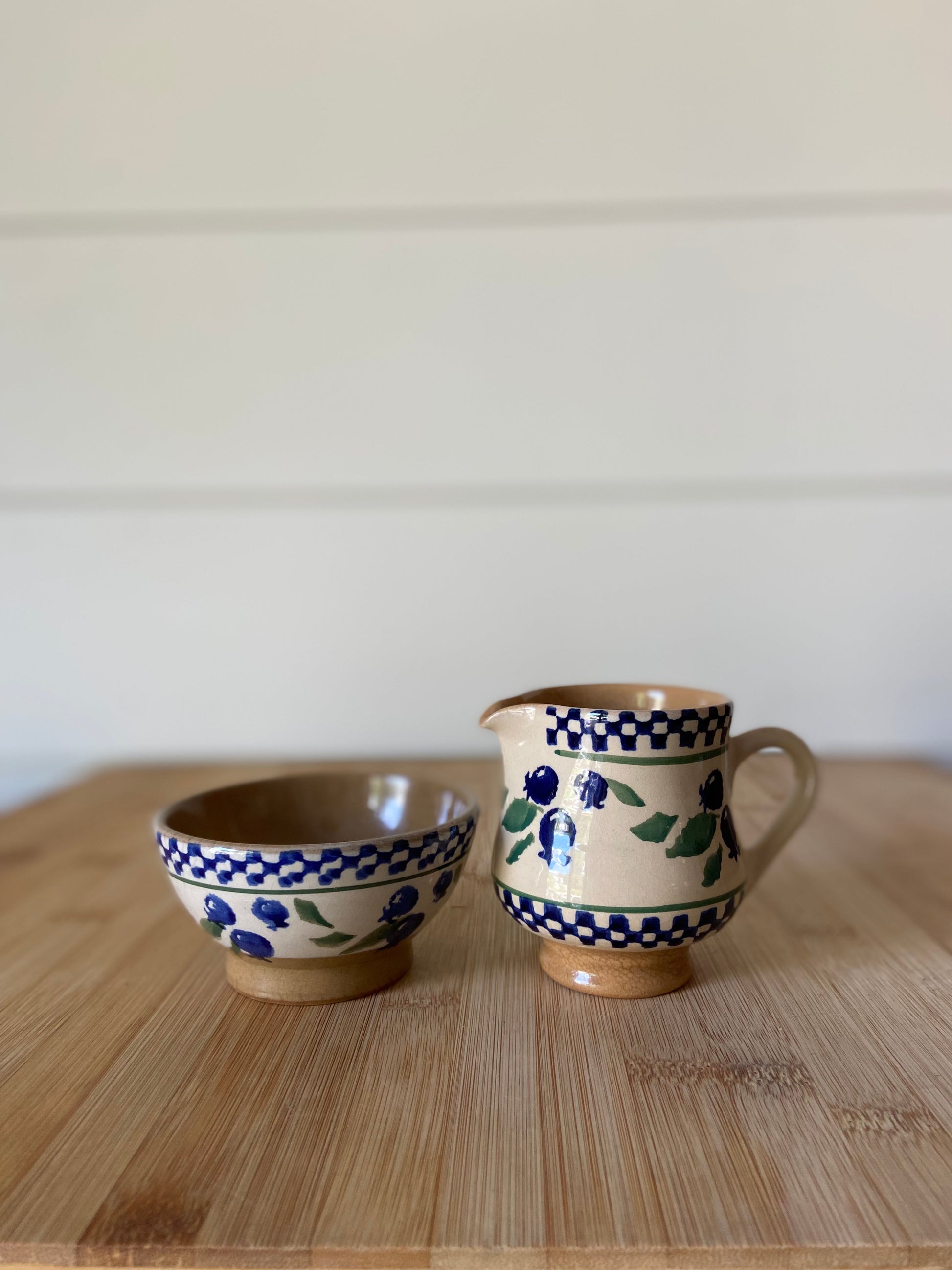 "A blue and white creamer and bowl set with a blueberry design, made in Ireland."