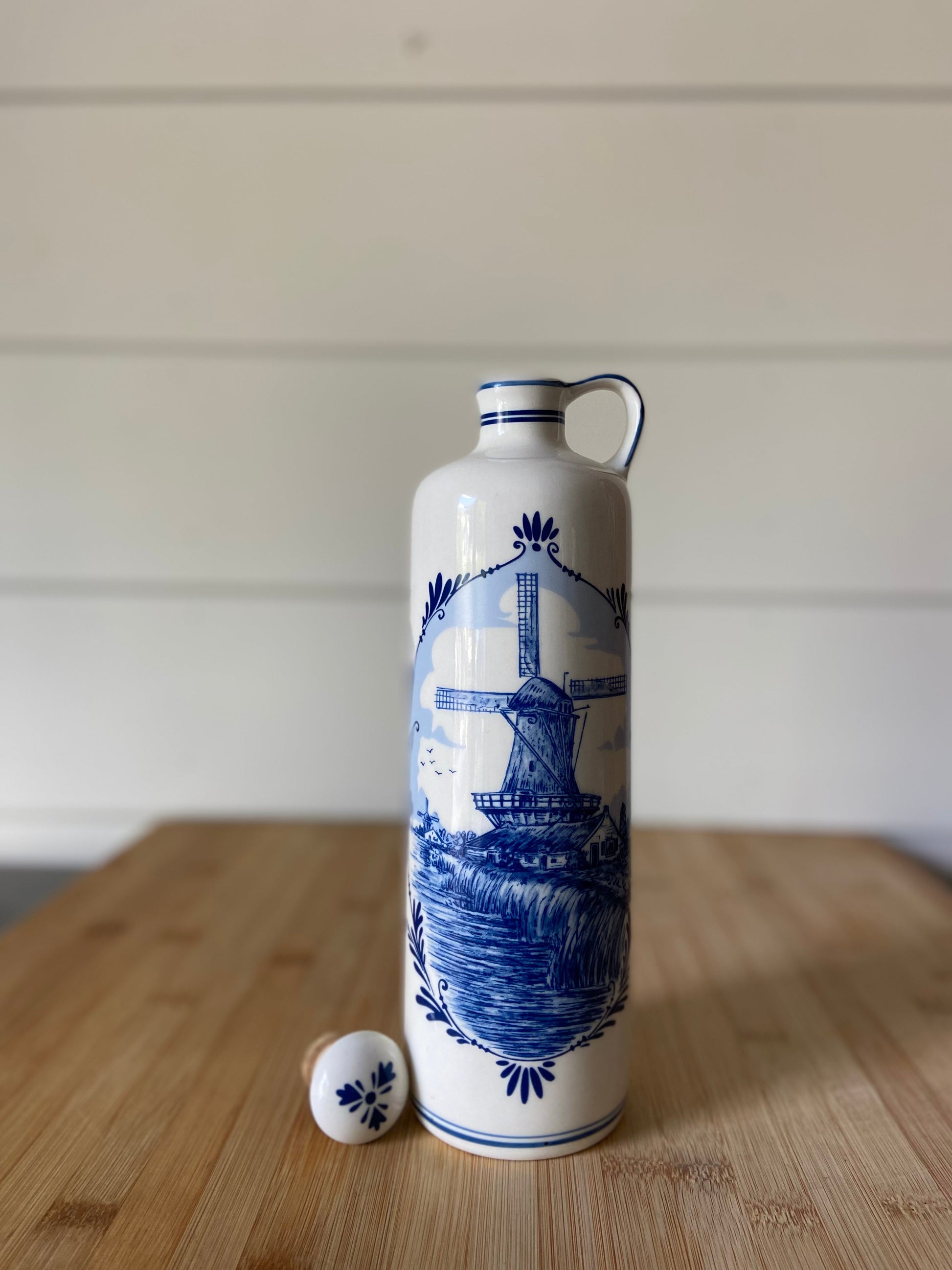 "A vintage blue and white decanter with a cork top, ideal for décor or as an olive oil dispenser."