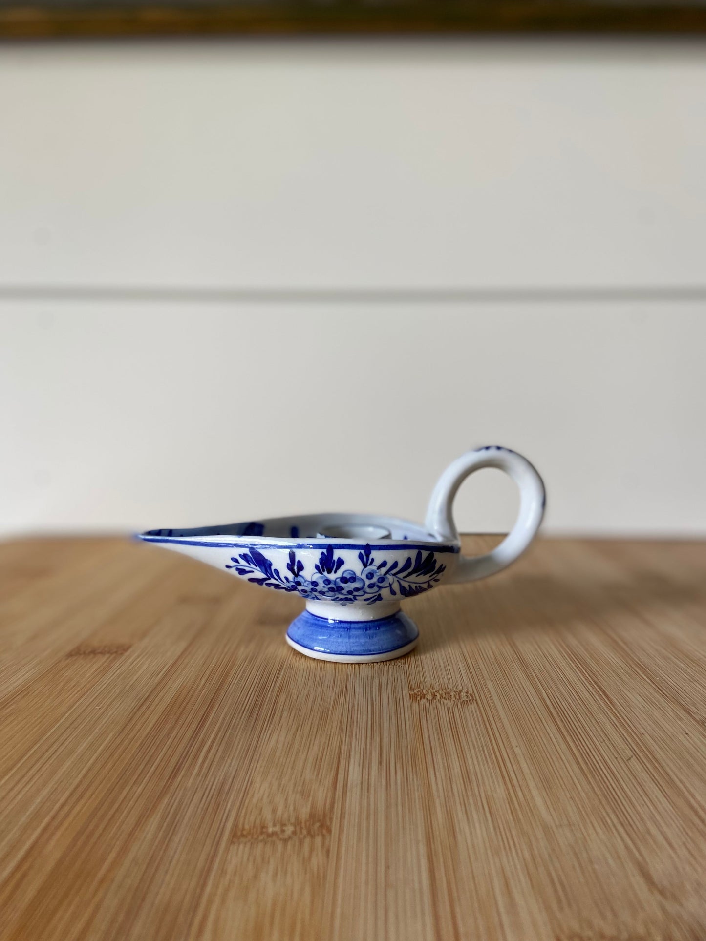 "A charming blue and white candle holder with a distinctive shape, similar to Delft designs."