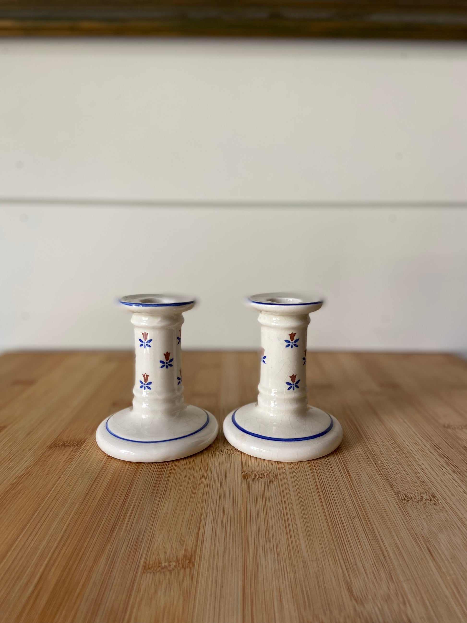 "Matching blue and white candle holders with delicate flower markings and solid blue lines."