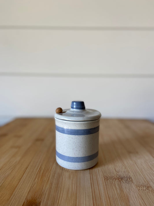 "A vintage McCoy ceramic honey pot with a wooden spoon, glazed in blue stripes."